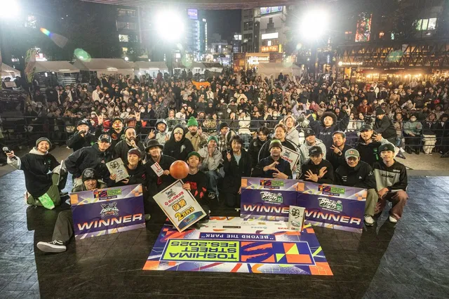 TOSHIMA STREET FES 2025の夜のステージで、WINNERの看板を掲げた出場者たちと大勢の観客が記念撮影をしている様子