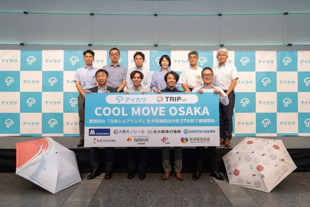 COOL MOVE OSAKA発表会で横断幕を掲げる関西8鉄道事業者とアイカサの関係者たち。Osaka Metro・大阪モノレール・北大阪急行電鉄・近鉄・京阪・南海・阪急・阪神のロゴが並ぶ