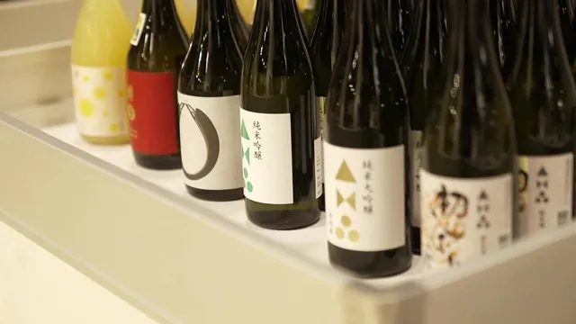 棚に並んだ純米吟醸や純米大吟醸など多種多様な日本酒のボトル群