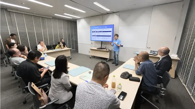 issin代表の程涛氏が会議室でオートケア構想のスライドを使いながらプレゼンテーションしている様子。十数名の聴衆が着席して聞いている