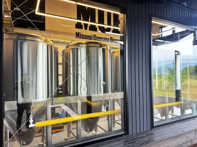 MUBG施設外側のガラス窓越しに見えるクラフトビール醸造用のステンレス発酵タンク群。Minami Uonuma Breweryの文字が上部に掲げられている