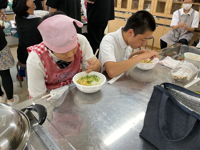 調理実習室で完成した鶏白湯らーめんを箸で食べる支援学校の生徒たち。丼にはメンマとネギがトッピングされている