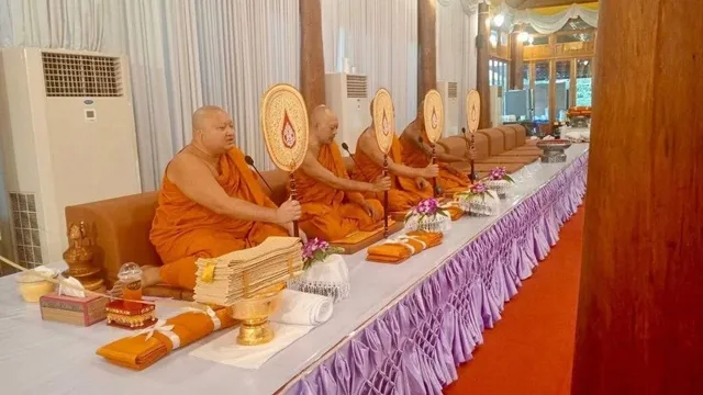 タイの提携寺院で読経を行う僧侶たち。オレンジの袈裟を纏い、経典の扇を手に座っている