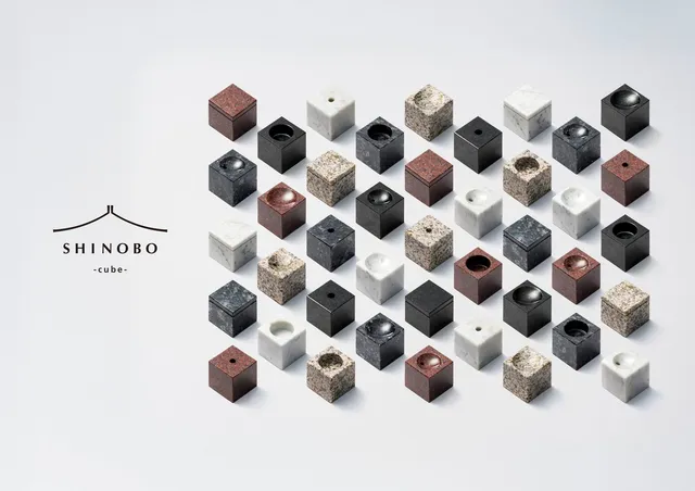 SHINOBO cubeの全バリエーション。白い大理石・ベージュの御影石・黒御影石・赤御影石など多色の60ミリ角キューブが整列し、花立て・香立て・火立て・水受け・形見入れの各エレメントの上部加工の違いが見える