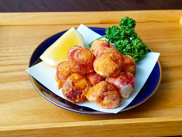 ほぼタコを唐揚げ風に揚げた料理。レモンとパセリを添えて皿に盛り付けられている