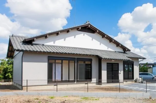 リノベーション後の白い外壁と瓦屋根の平屋住宅、玄関前にフェンスと駐車スペース