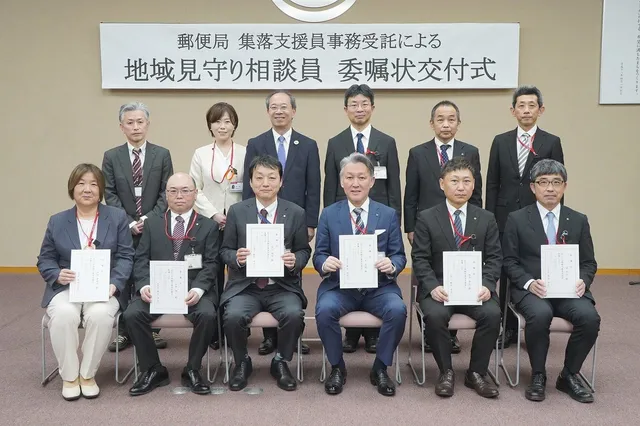 郵便局集落支援員事務受託による地域見守り相談員委嘱状交付式で、委嘱状を手に並ぶ郵便局長らと市職員