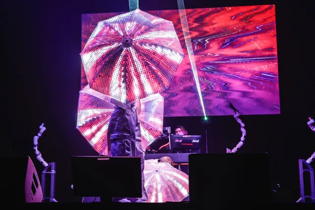 LED VISION UMBRELLAを掲げるパフォーマーと、視線入力で操作するDJブースの武藤将胤さん