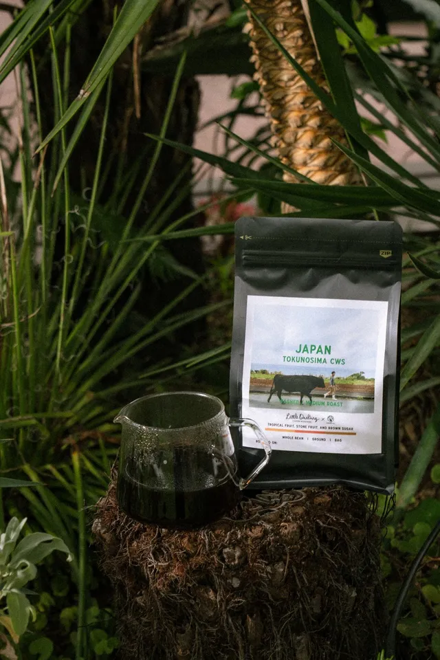 抽出されたコーヒーとECHO COFFEE TOKUNOSHIMAのパッケージが植物に囲まれて置かれている