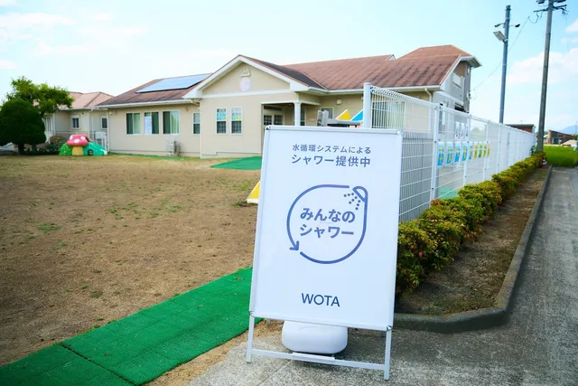 保育園の敷地に設置された「みんなのシャワー」の案内看板とWOTAの機材