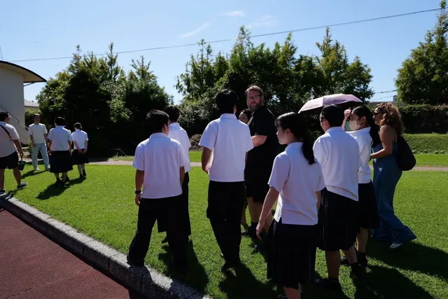 学校の校庭で地元の学生と外国人参加者が交流している様子