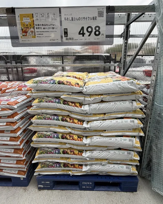 カインズ店舗の売場に積まれた牛めし屋さんのリサイクル堆肥の袋。498円の価格札とともに陳列されている