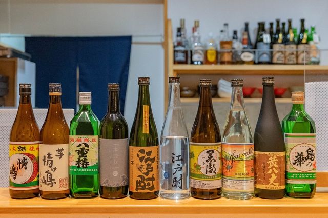 カウンターに並べられた八丈島焼酎の多彩な銘柄のボトル群